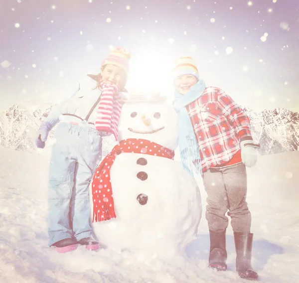 Kinderen met plezier met sneeuwpop — Stockfoto