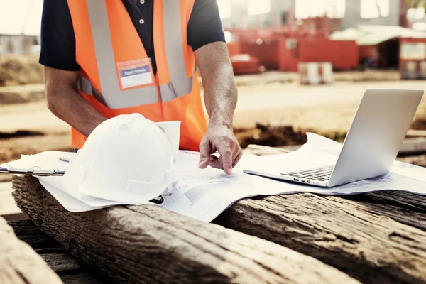 Trabalhador de construção examina desenhos — Fotografia de Stock