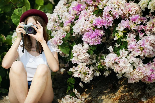 Frau mit Kamera umgeben von Blumen — Stockfoto