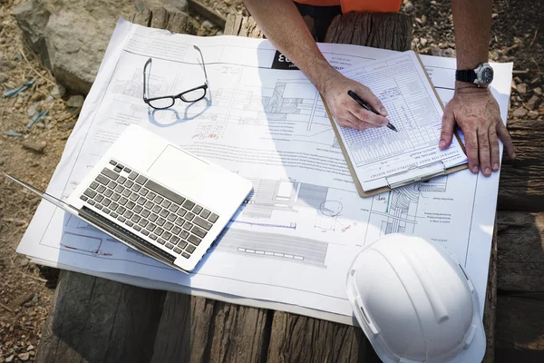 Trabalhador de construção examina desenhos — Fotografia de Stock