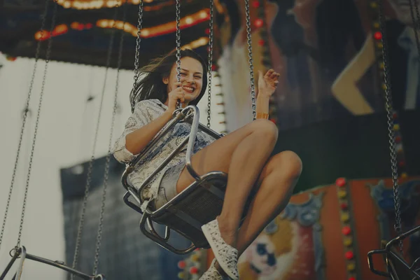 Flicka som rider på swing i nöjesparken — Stockfoto