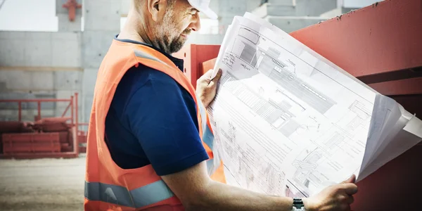 Trabalhador de construção examina desenhos — Fotografia de Stock