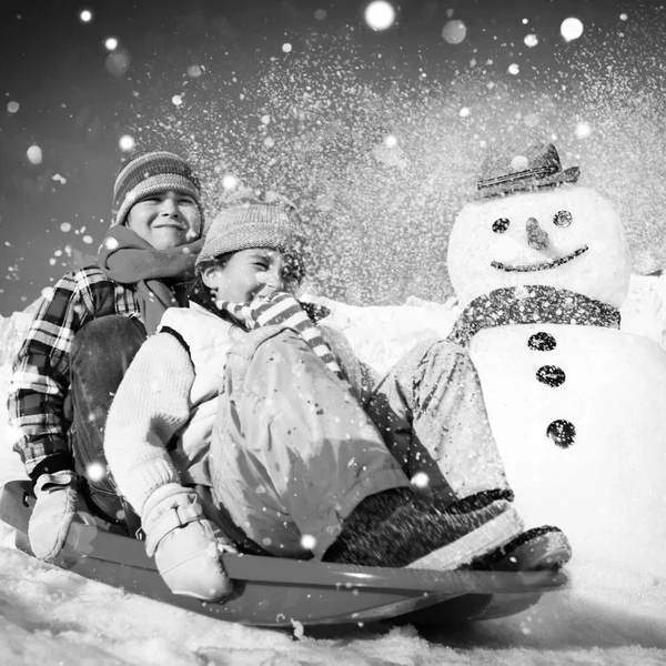 Children riding on snow sledge — Stockfoto