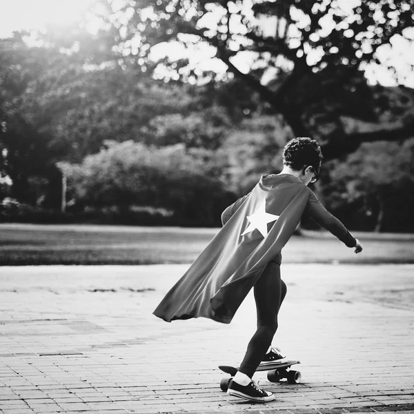 Superhjälte ungen ridning på skateboard — Stockfoto