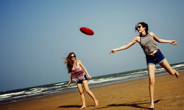 Meisjes op het strand spelen frisbee — Stockfoto