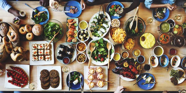 Amigos com diferentes alimentos e bebidas — Fotografia de Stock
