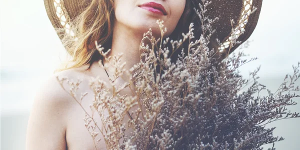 Mujer sosteniendo flores en la playa — Foto de Stock