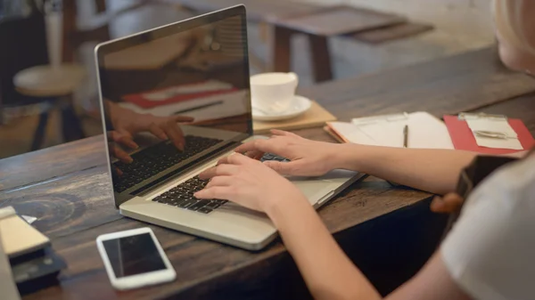 Женщина в кафе работает с компьютером — стоковое фото