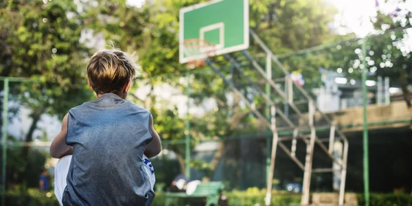 Jongen zit op basketbal stadion — Stockfoto
