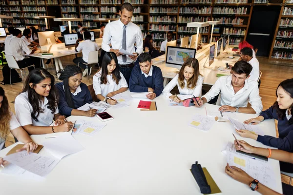 Professor com alunos na biblioteca — Fotografia de Stock