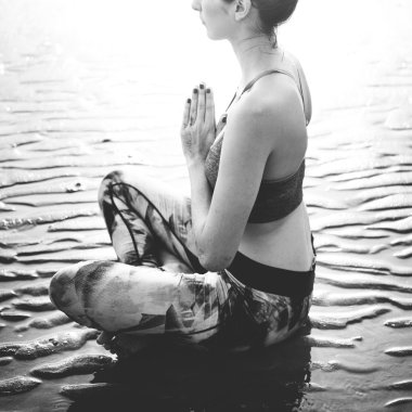 Plajda yoga yapan bir kadın.