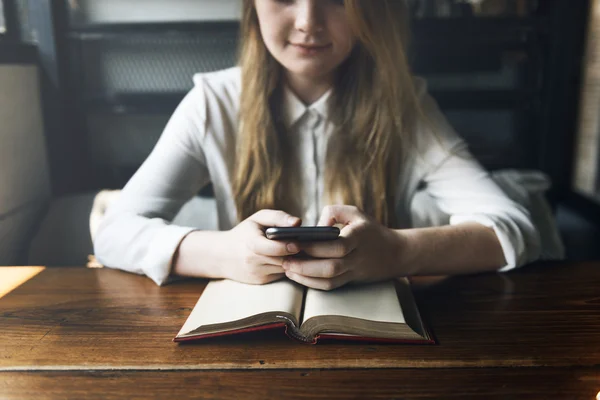 Ung flicka med telefonen i café — Stockfoto