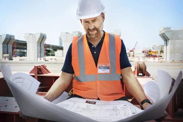 Trabalhador da construção Olhando para o plano de construção — Fotografia de Stock