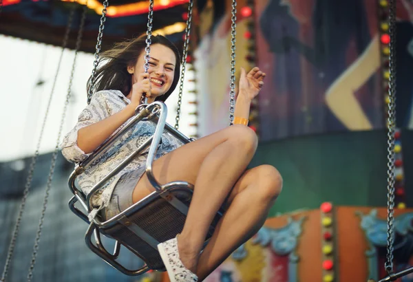 Meisje paardrijden op schommel in attractiepark — Stockfoto