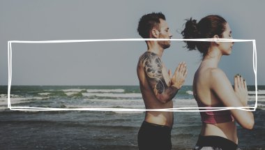 Çiftler plajda yoga yapıyor.