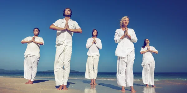 Människor som utför yoga på stranden — Stockfoto