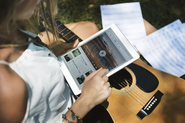 Девушка с гитарой с помощью планшета — стоковое фото