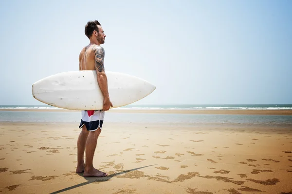 Człowiek z deską surfingową na plaży — Zdjęcie stockowe
