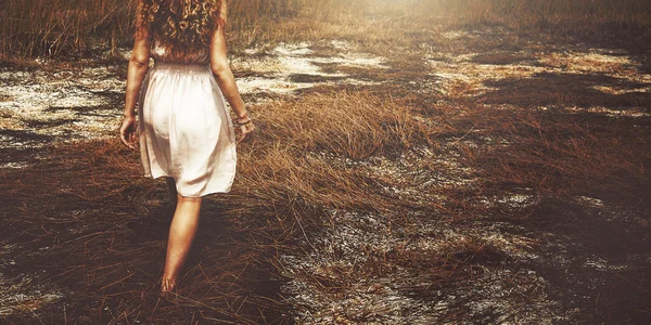 Kvinnan promenader på torrt gräs — Stockfoto