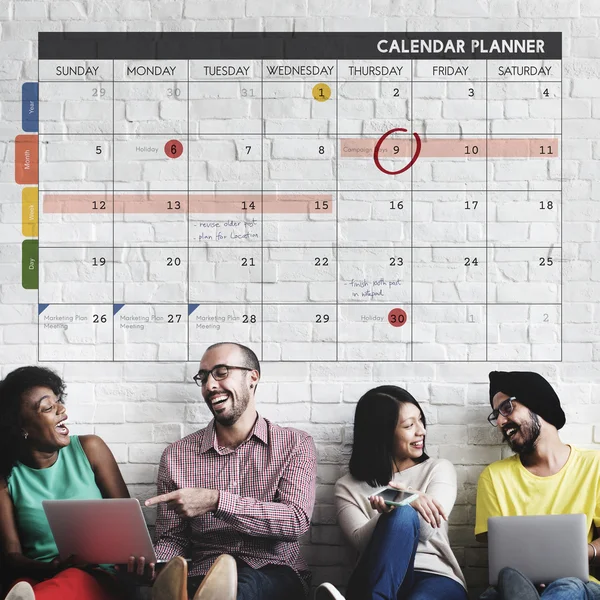Mångfald vänner nära väggen med kalender — Stockfoto