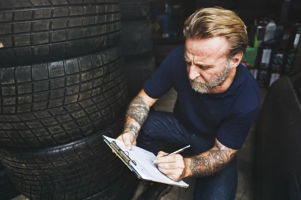 Carro mecânico escrevendo notas na garagem — Fotografia de Stock