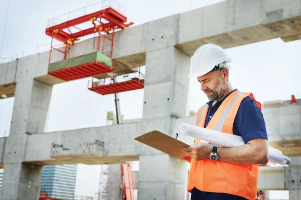 Trabalhador da construção Olhando para o plano de construção — Fotografia de Stock