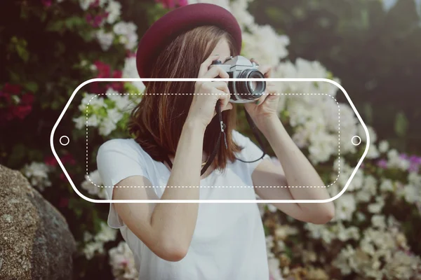 Vrouw met camera omringd door bloemen — Stockfoto