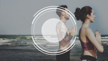 Çiftler plajda yoga yapıyor.