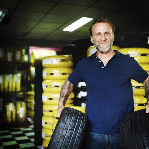 Mužské mechanik drží auto pneumatiky — Stock fotografie