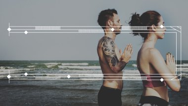 Çiftler plajda yoga yapıyor.