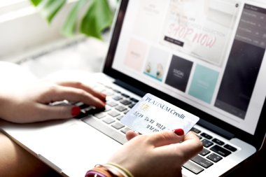 Bilgisayarı ve kredi kartı olan bir kadın.