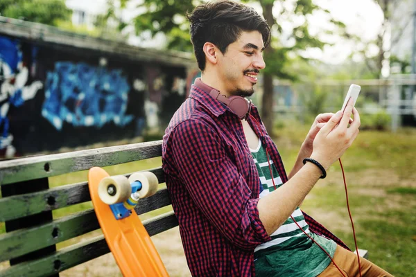 Skate homem segurando telefone inteligente — Fotografia de Stock