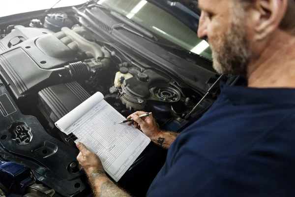 Mechanik mężczyzna pisać notatki o samochód — Zdjęcie stockowe