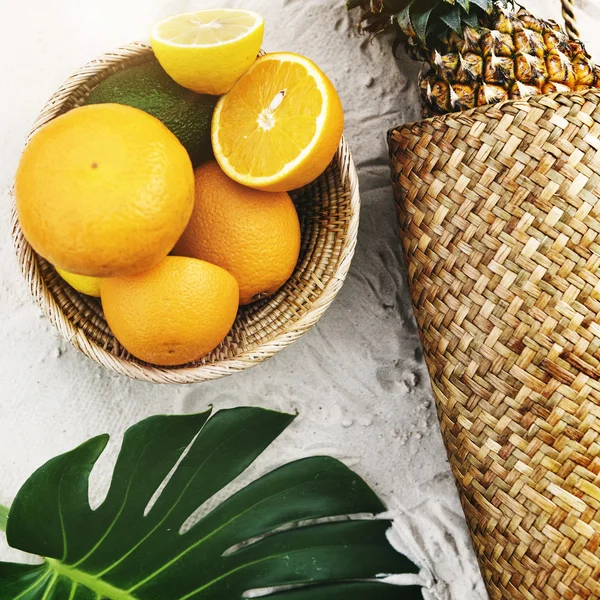 Pineapple and oranges on beach sand — Stock Photo, Image