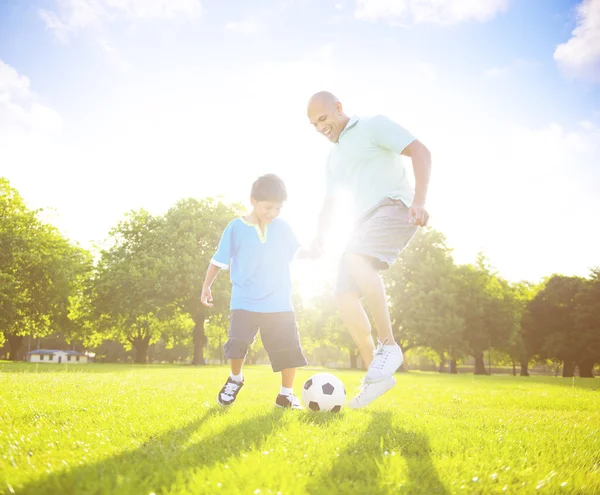 Отец играет в футбол с маленьким сыном — стоковое фото