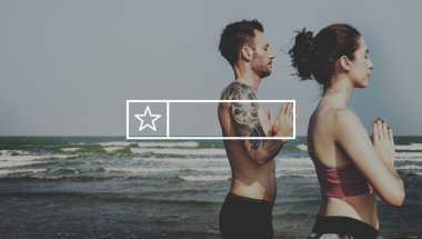 Çiftler plajda yoga yapıyor.