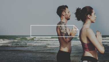 Çiftler plajda yoga yapıyor.