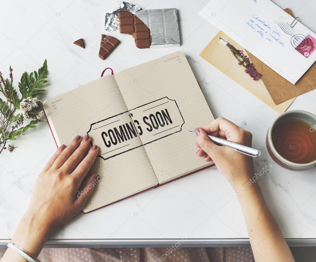 Person using notebook for notes, Stamp Concept. Text: Coming Soon