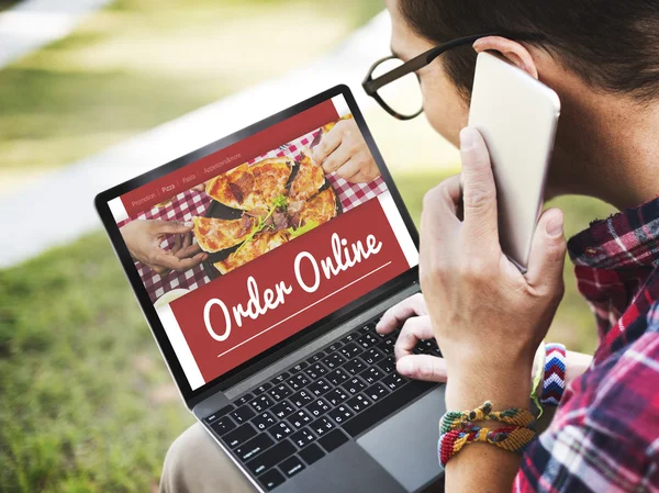 Man with Smartphone Browsing on Laptop — Stockfoto