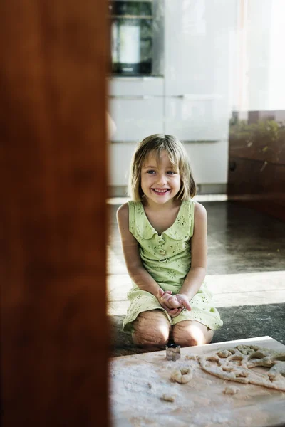 Meisje zit in de buurt van deeg — Stockfoto