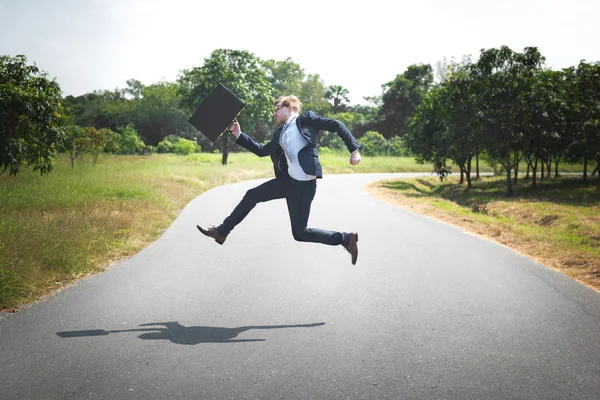 Empresário ao ar livre saltando com caso — Fotografia de Stock