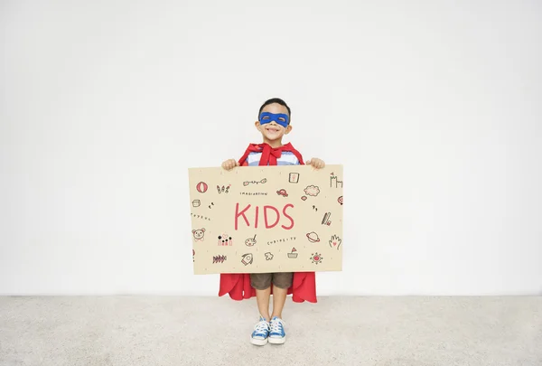 Superheld jongen met karton in handen — Stockfoto