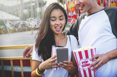 Eğlence parkında telefon kullanarak çift