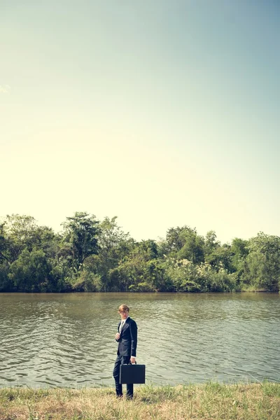 Homme d'affaires avec mallette à la rivière — Photo