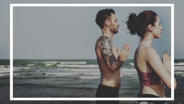 Çiftler plajda yoga yapıyor.