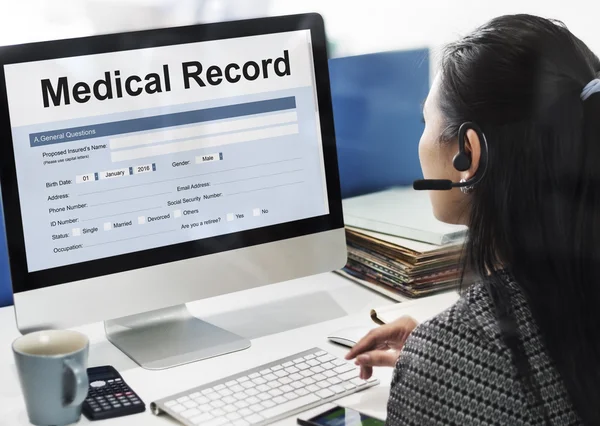 Mujer de negocios que trabaja en la computadora con historial médico — Foto de Stock