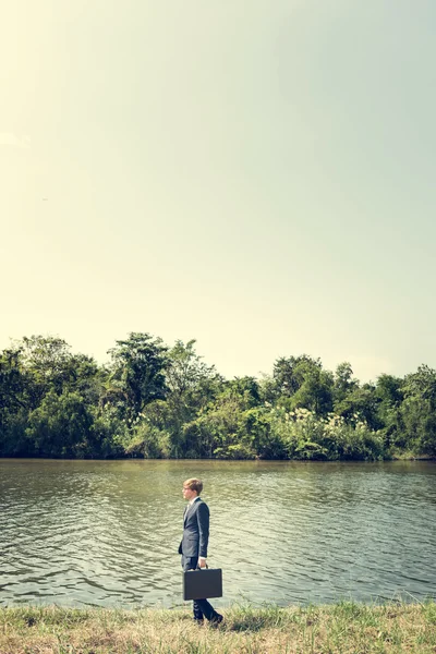 Podnikatel s Aktovkou stojí u řeky, — Stock fotografie