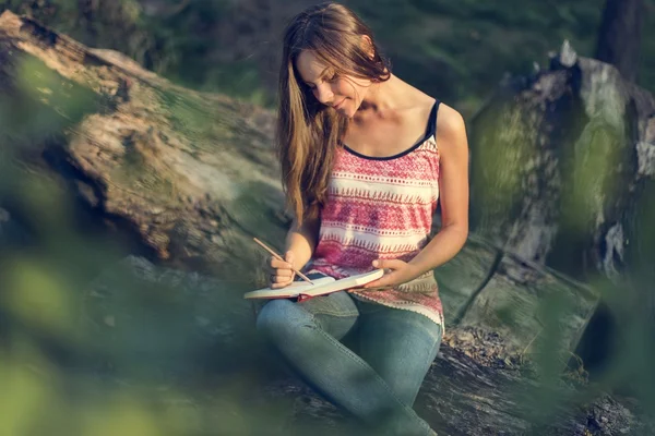 Frau schreibt Notizen in der Natur — Stockfoto