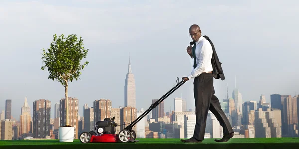 Зеленый бизнесмен стрижет газон — стоковое фото