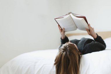 Coronavirus karantinası sırasında yatağında kitap okuyan bir kadın.
